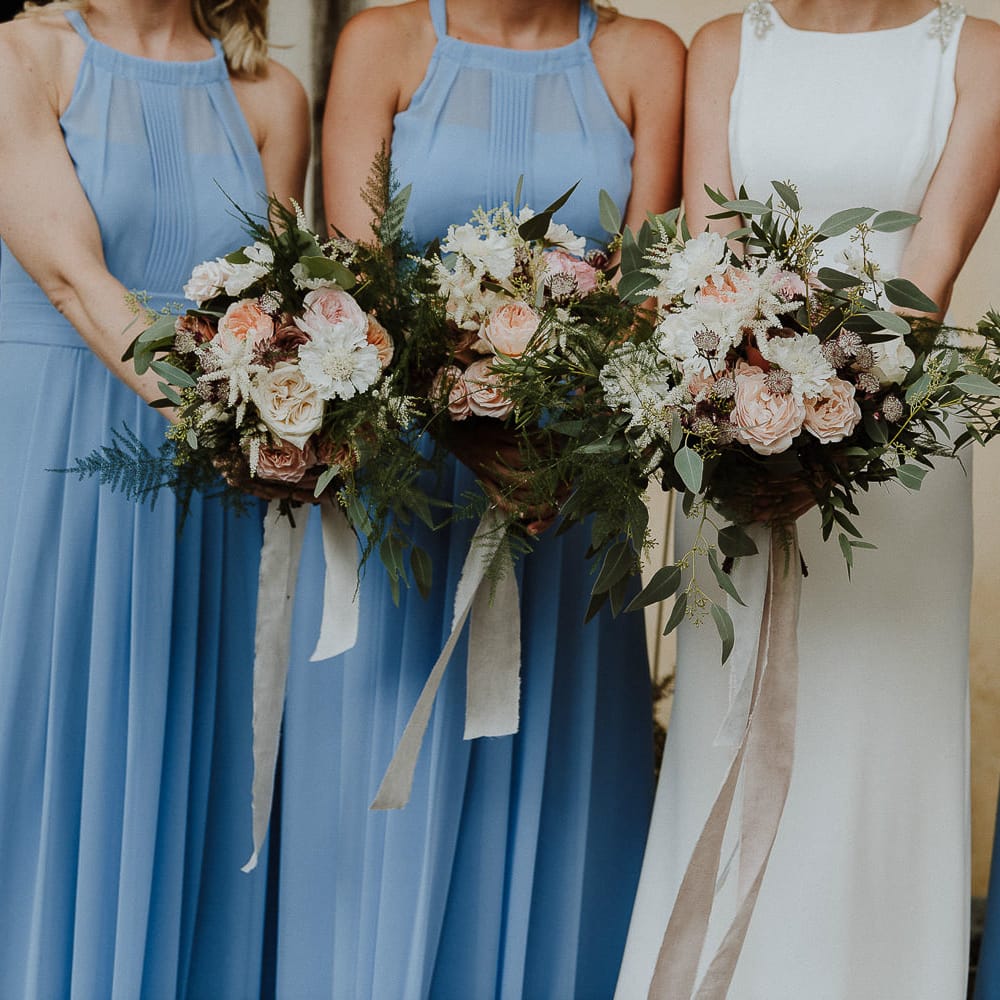 Bride and Bridesmaids in Blue Halterneck Dresses Holding Their Bouquets