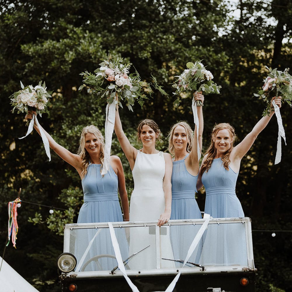 Bridal Party Portrait with Bridesmaids in Blue Halterneck Dresses and Bride in Makaella Bridal Wedding Dress Holding up Their Bouquets in The Wedding Car