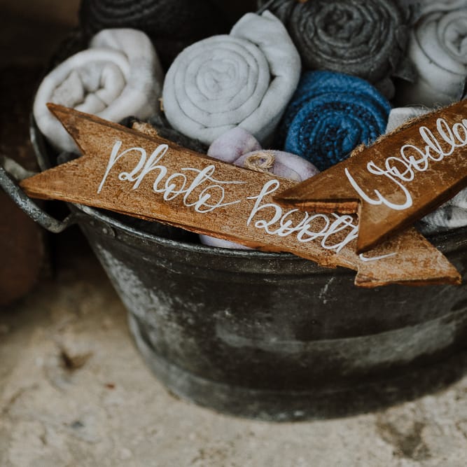 Metal Basket Filled with Rolled Blankets and Wooden Arrow Wedding Signs