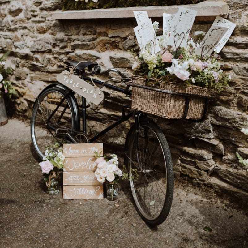 Vintage Bicycle Basket Filled with Flowers as a Wedding Table Plan with Wooden Signs