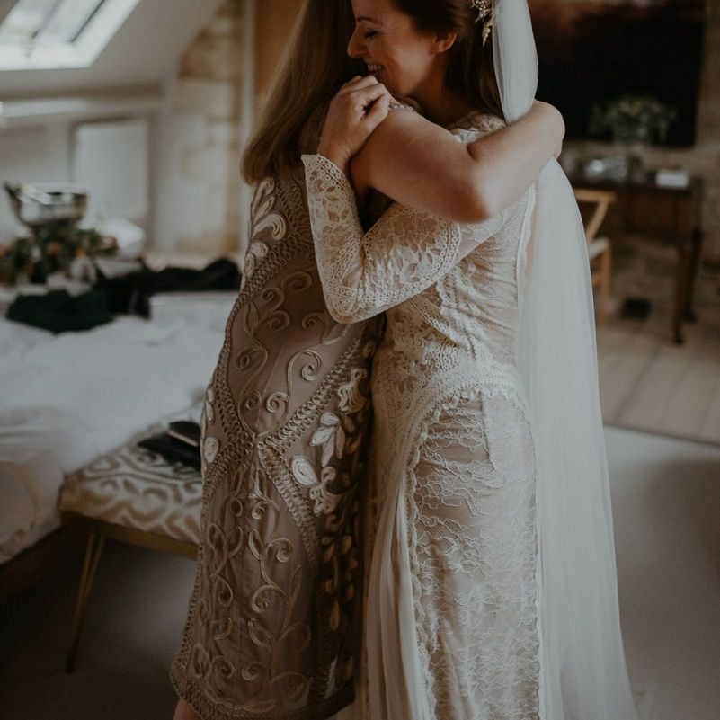 Bride and bridesmaid hugging on wedding morning