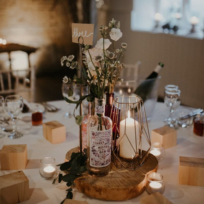 Rustic centrepiece decor with tree slice, terrarium, gin bottles and flowers
