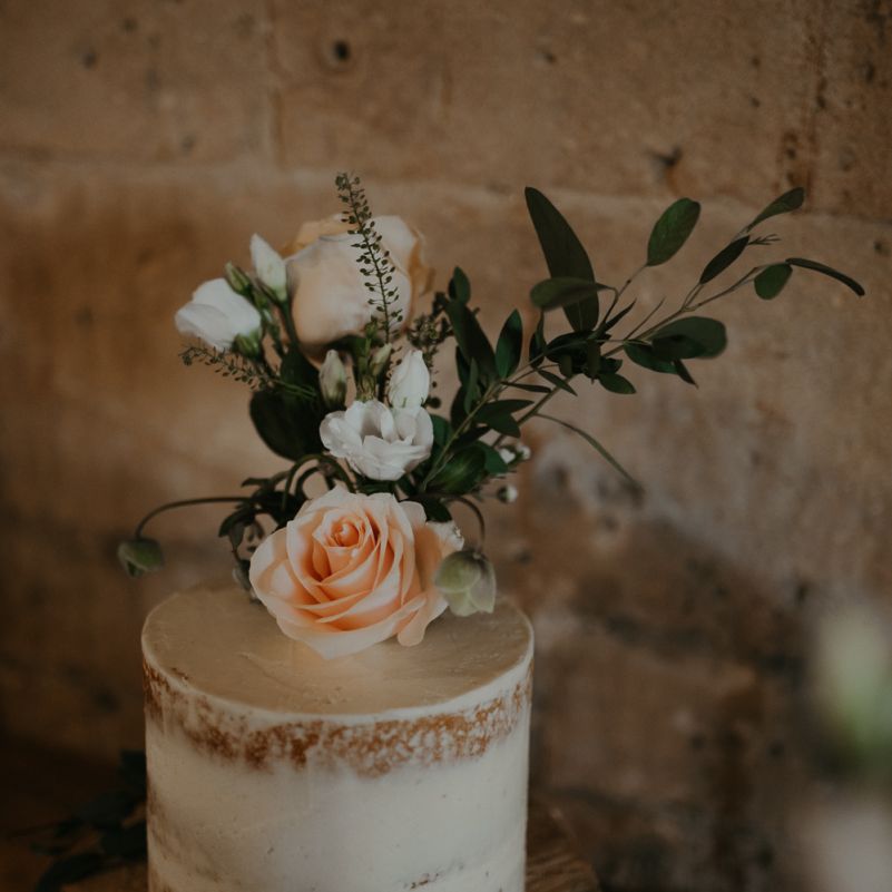 Small semi naked wedding cake with flower topper