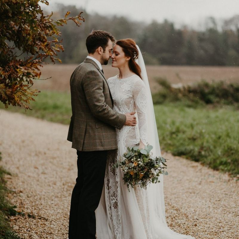 Groom in wool blazer embracing his bride in Grace Loves Lace wedding dress