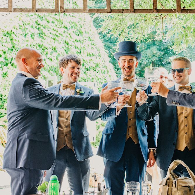 Groom in Blue Two Piece Suit with Tan Waistcoat, Bow Tie and Top Hat | Colourful Bunting Wedding Decor for a Festival Themed Marquee Wedding | Peppermint Love Photography
