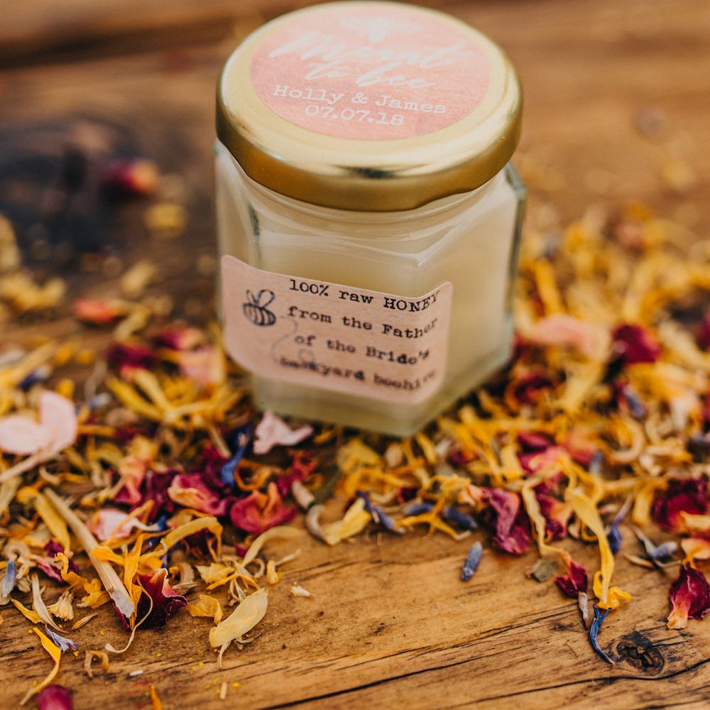 Hexagon Pot of Honey for Wedding Favour | Dried Scattered Petals | Colourful Bunting Wedding Decor for a Festival Themed Marquee Wedding | Peppermint Love Photography
