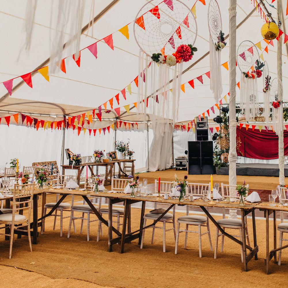 Bright Bunting in Marquee | Dreamcatchers | Colourful Tapered Candles | Wooden Banquet Tables | Wedding Reception Décor | Colourful Bunting Wedding Decor for a Festival Themed Marquee Wedding | Peppermint Love Photography