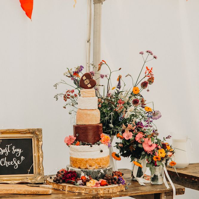 Nine Tier Cheese Cake | Rustic Wooden Table | Bright Wild Flowers | Colourful Bunting Wedding Decor for a Festival Themed Marquee Wedding | Peppermint Love Photography