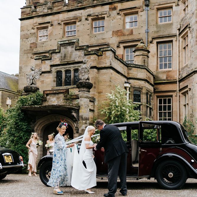 Bride in Savannah Miller wedding dress getting into a vintage wedding car