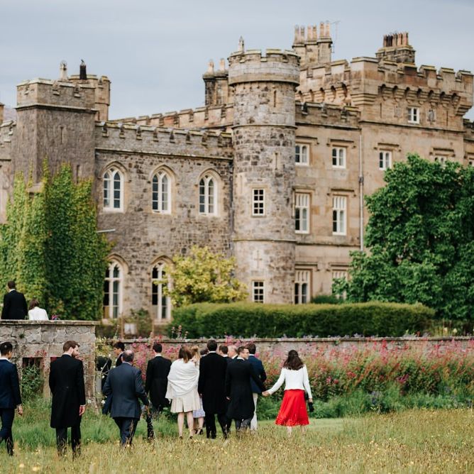 Guests and family walk across the lawn towards Hawarden Castle for the drinks reception