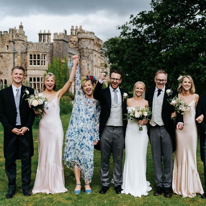 Posed family photograph of bride, groom and bride's family with Hawarden Castle in the background