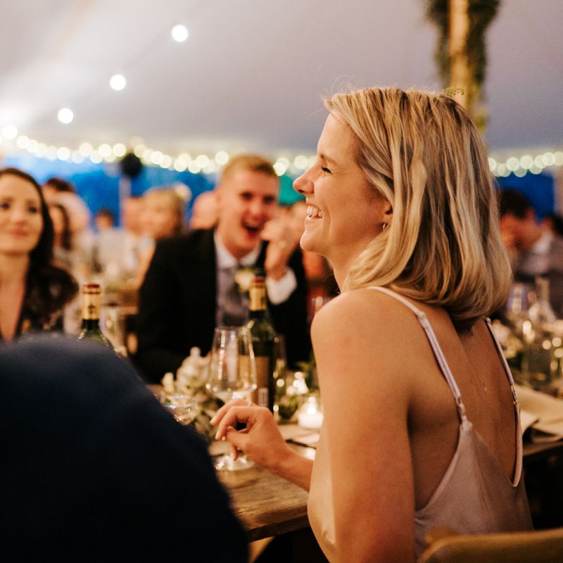 Sister of the bride smiles graciously during groom's speech