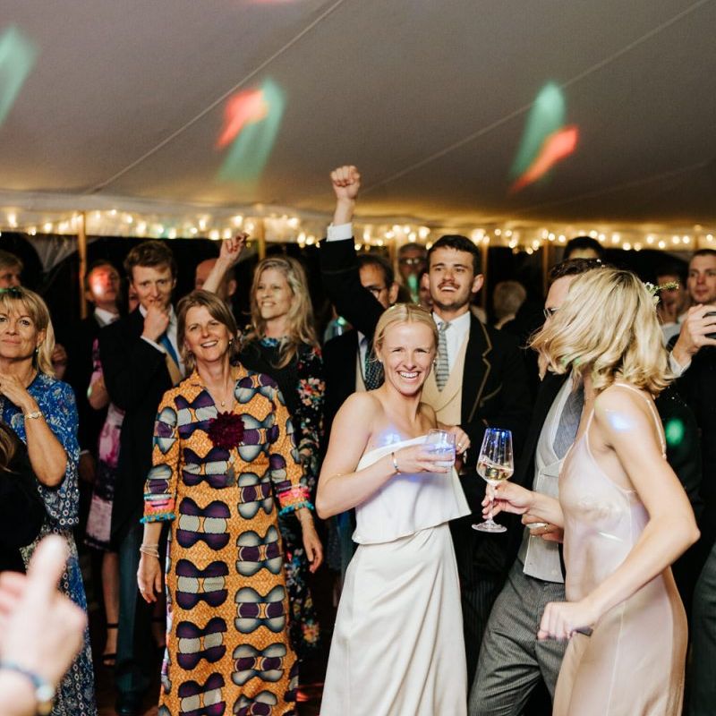 Bride smiles in front of dancefloor as she is wearing her second outfit of the day