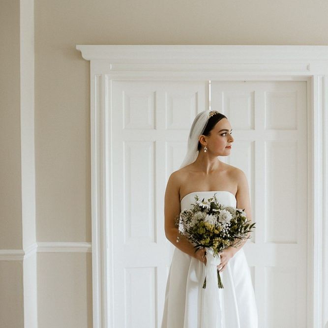 Bride Holds Bouquet In Front Of Strapless Wedding Dress