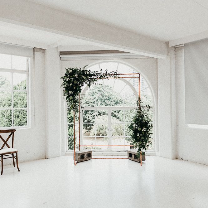 Wedding Ceremony Decor | Copper Arch with White Flowers and Foliage | Whitewashed Walls | Same Sex Wedding with Industrial Styling at Wimborne House | Marmelo Photography