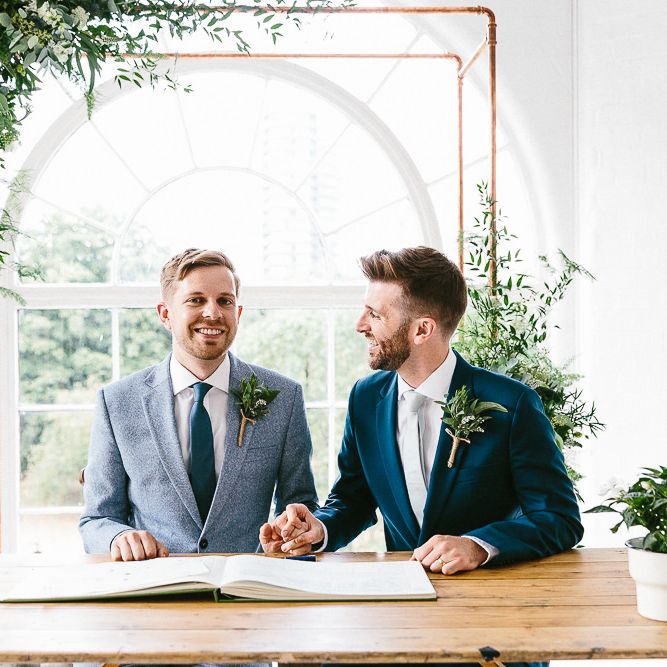 Signing of Register | Copper Arch with White Flowers and Foliage | Groom in Dark Petrol Blue Suit by Paul Smith | Groom in Light Blue Made To Measure Suit by Beggars Run | Same Sex Wedding with Industrial Styling at Wimborne House | Marmelo Photography