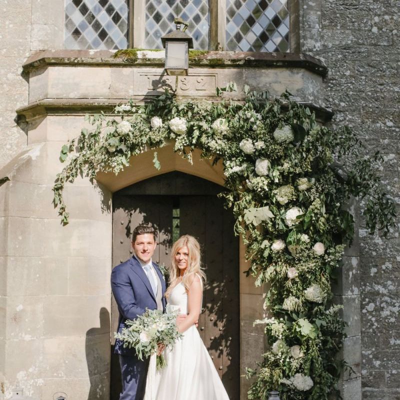 Bride and groom portrait outside the church under floral arch