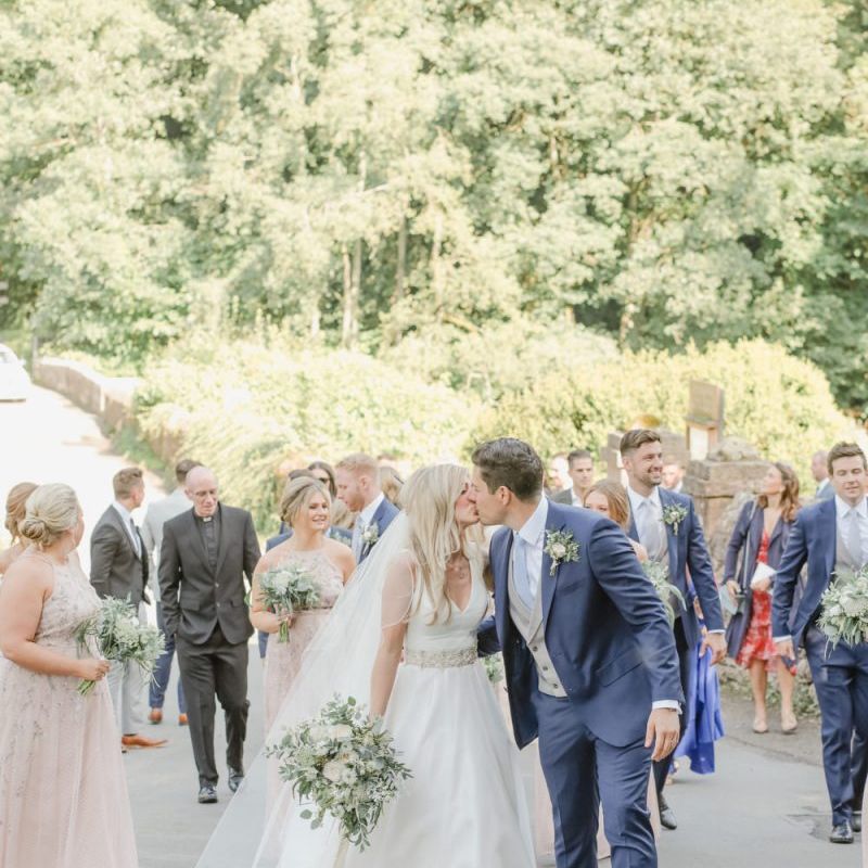 Bride and groom kissing in the church courtyard