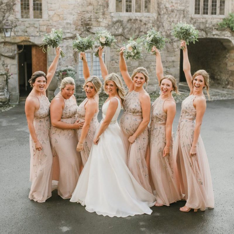 Bridal party portrait with bride and bridesmaids holding their bouquets in the air