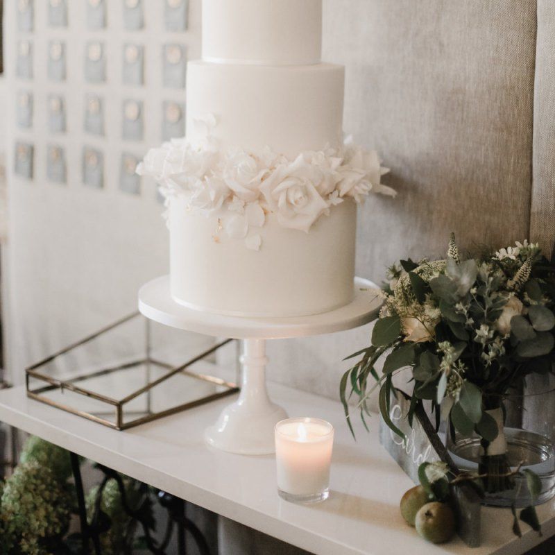 Elegant white wedding cake with wax seal escort card backdrop