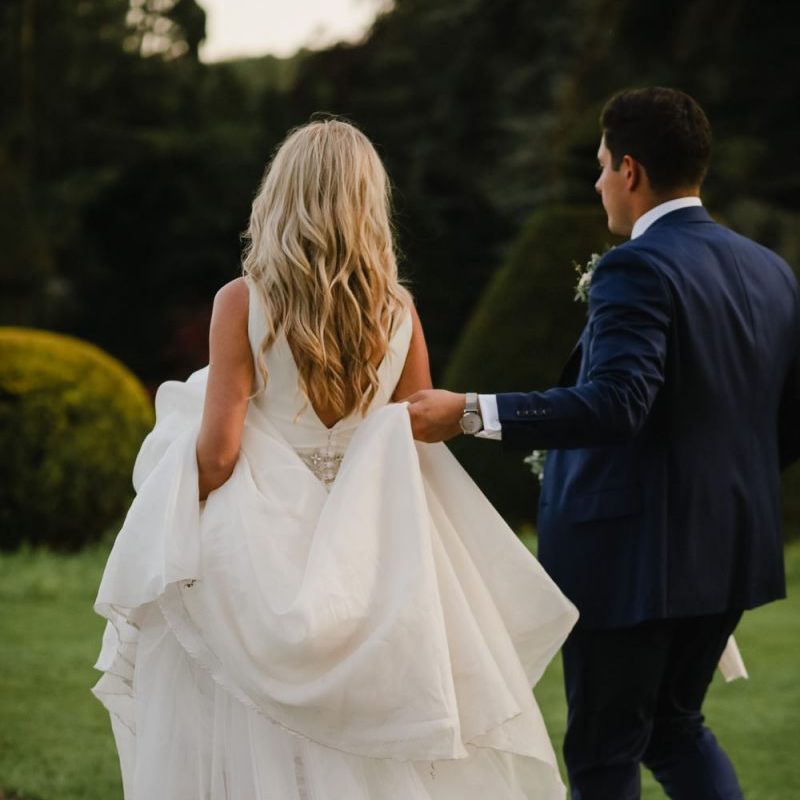 Groom helping his bride with her Sassi Holford wedding dress