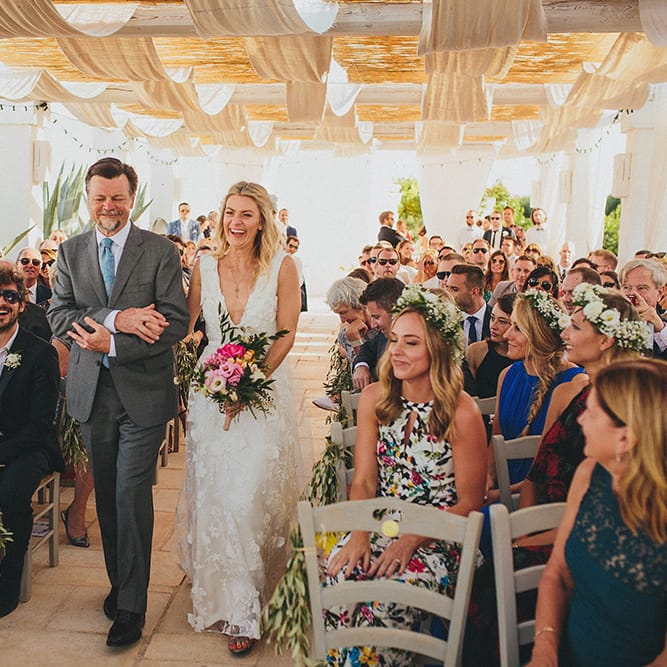 Outdoor Wedding Ceremony | Bridal Entrance in Custom Clemence Halfpenny London Bridal Gown | Brightly Coloured Destination Wedding at Masseria Potenti Wedding Venue, Puglia, South Italy | Petar Jurica Photography | Marco Odorino Film
