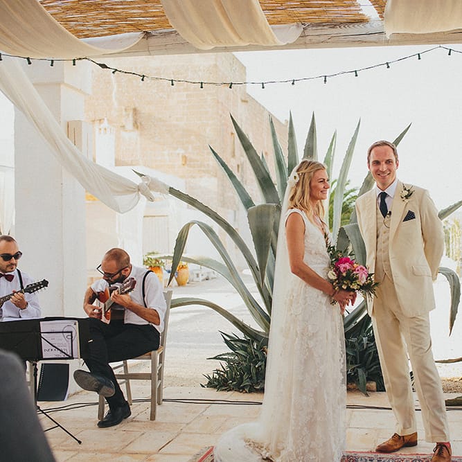 Outdoor Wedding Ceremony | Bride in Custom Clemence Halfpenny London Bridal Gown | Groom in Cream Three Piece Suit | Brightly Coloured Destination Wedding at Masseria Potenti Wedding Venue, Puglia, South Italy | Petar Jurica Photography | Marco Odorino Film