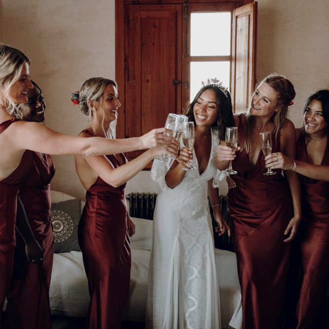 bride and bridal party sipping champagne on wedding morning with bride in Lace Loves Lace dress