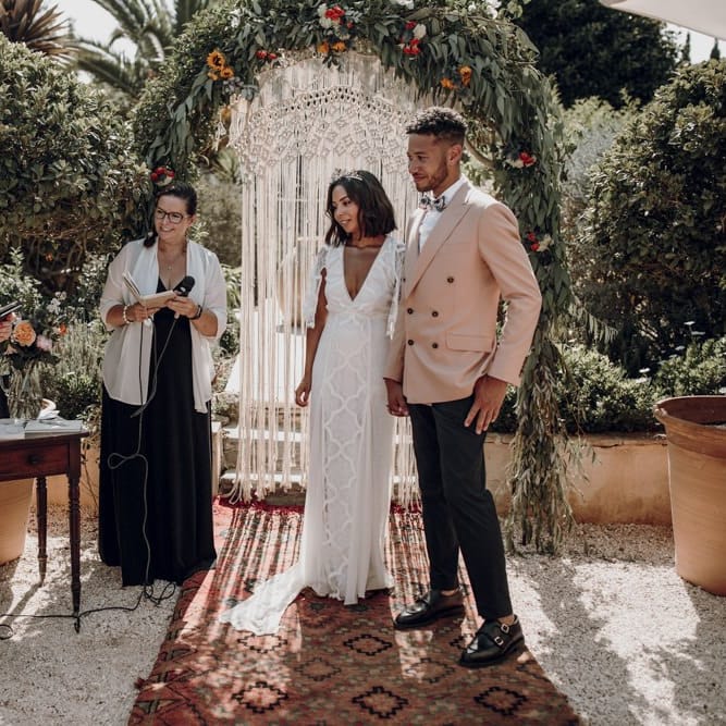 Outdoor wedding ceremony with floral arch, hanging macrame and Moroccan rugs