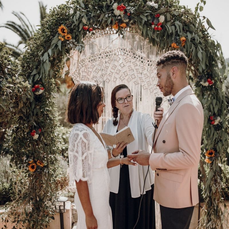 Bride and groom exchanging wedding rings during the ceremony with bride in Grace Loves Lace dress