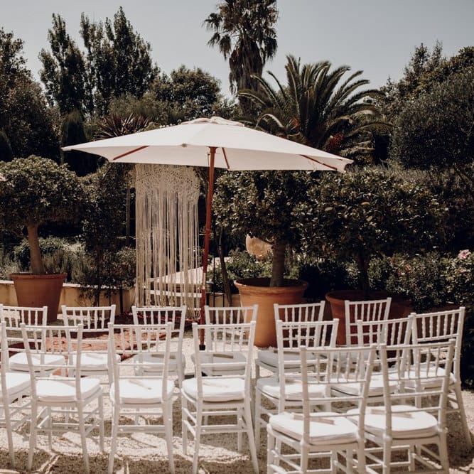 Outdoor wedding ceremony with parasols and macrame backdrop