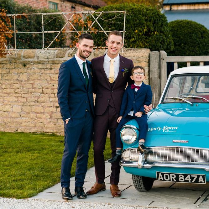 Grooms in Burgundy and Navy Remus Uomo Suits Standing Next to Ford Anglia Wedding Car