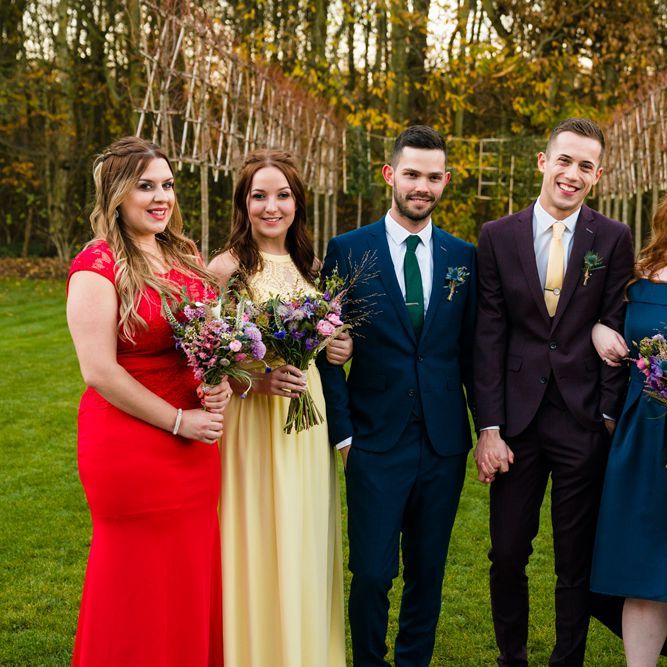 Two Grooms in Burgundy and Navy Remus Uomo Suits and Bridesmaids in Bright Dresses