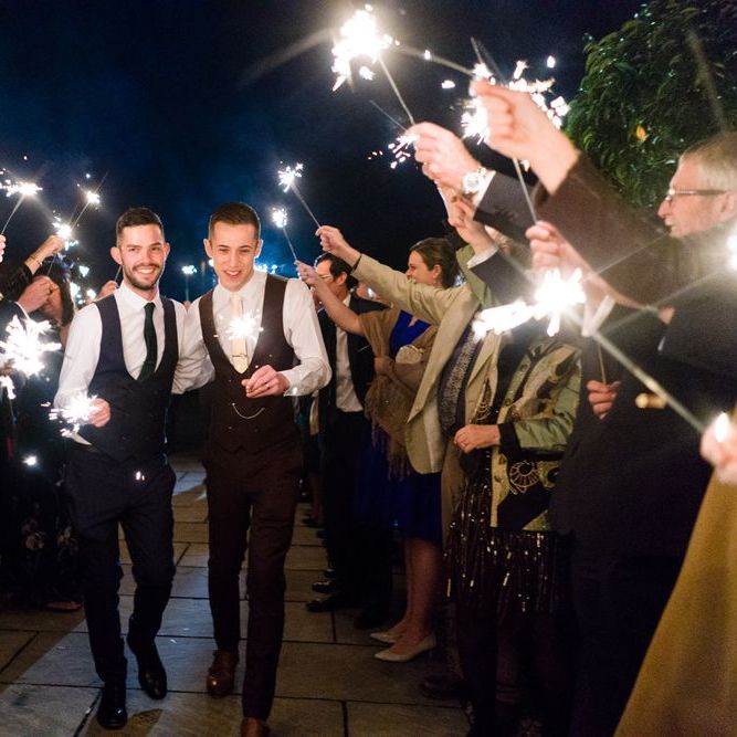 Two Grooms in Burgundy and Navy Remus Uomo Suits during Sparkler Moment