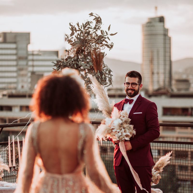Groom in burgundy suit waiting at the altar