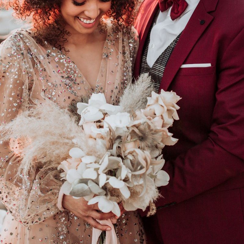Bride in sparkle wedding dress holding a orchid and pampas grass bouquet