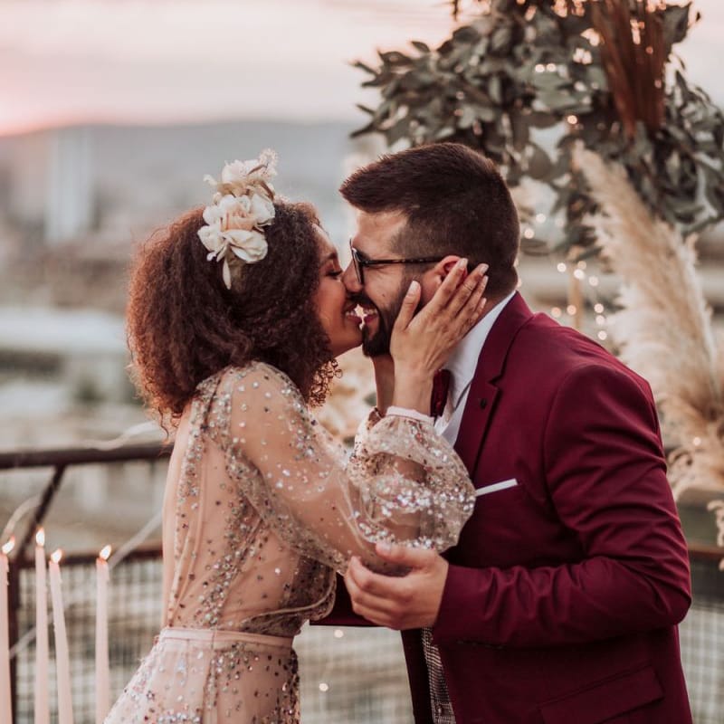 Bride in sparkle wedding dress kissing her groom in a red suit