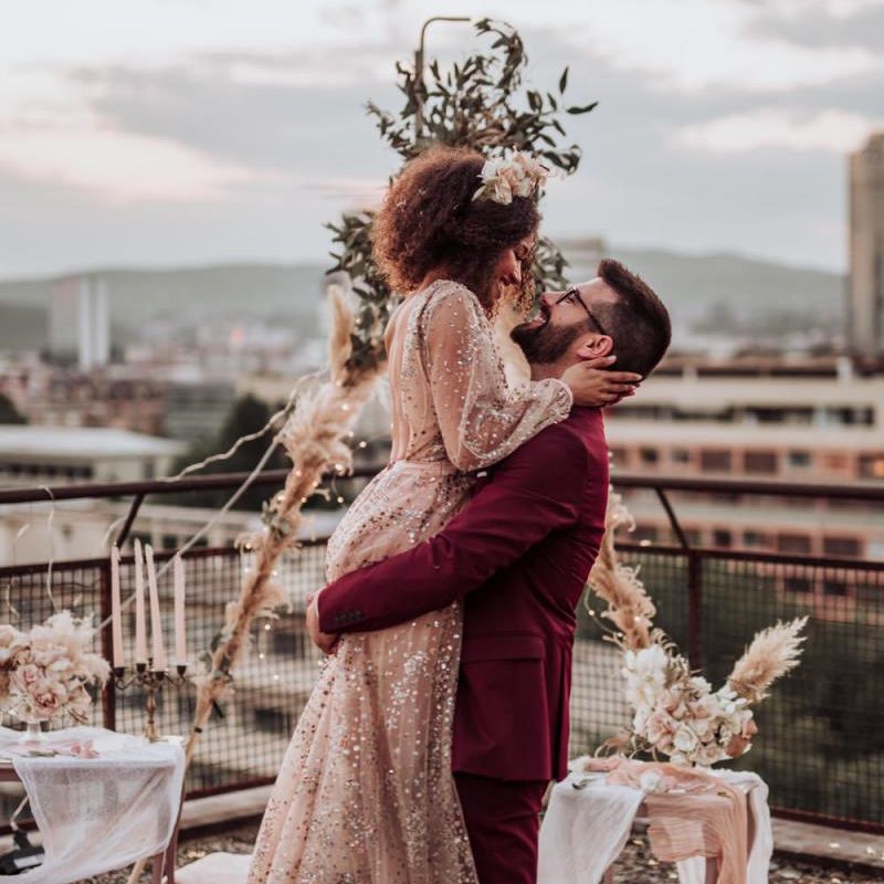 Bride in sparkle wedding dress and groom in burgundy suit at intimate boho wedding