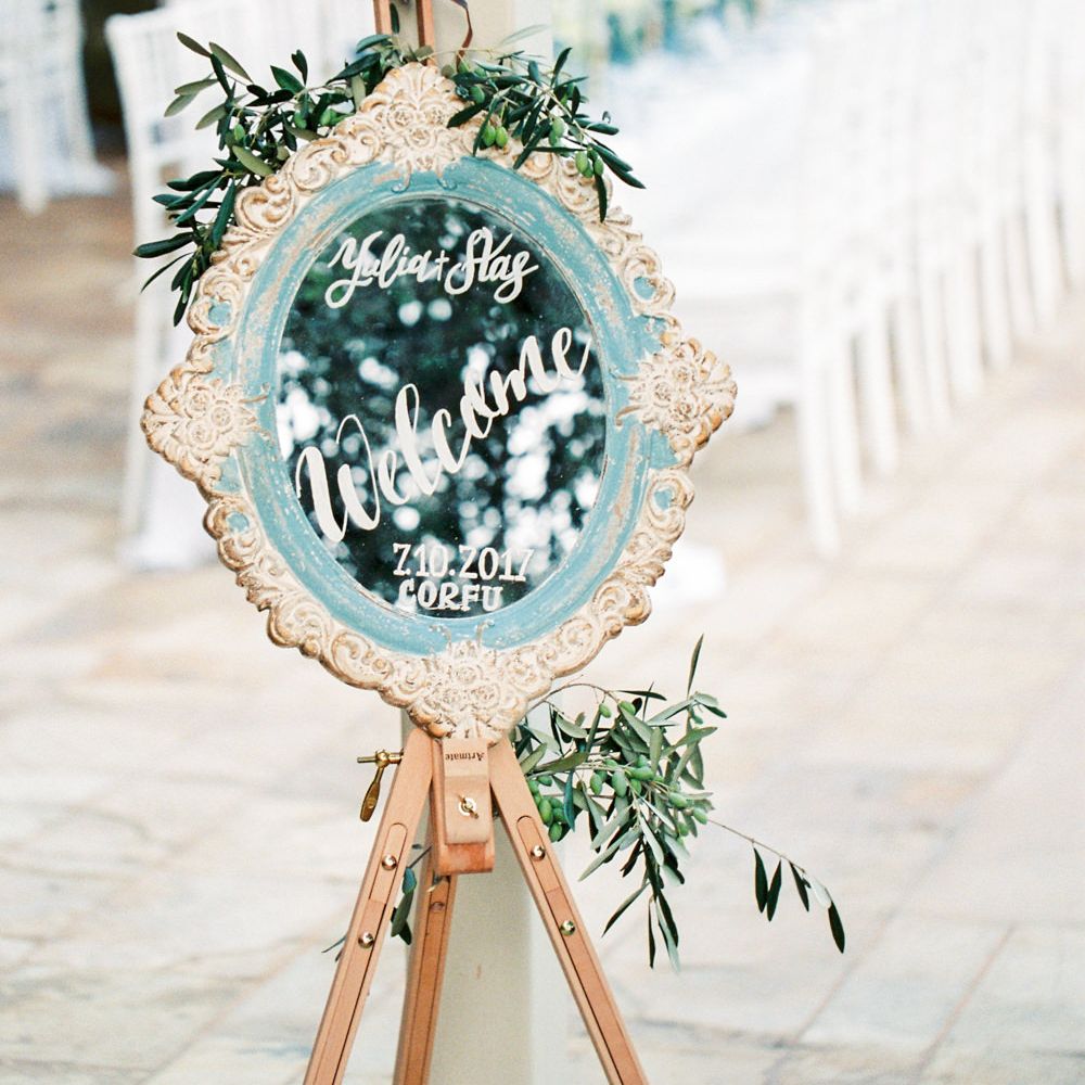 Mirror Welcome Sign on Easel  | Pastel Blue &amp; Green, Romantic, Destination Wedding at Corfu Luxury Villas, Planned by Rosmarin Weddings &amp; Events | Mikhail Balygin Fine Art Wedding Photographer