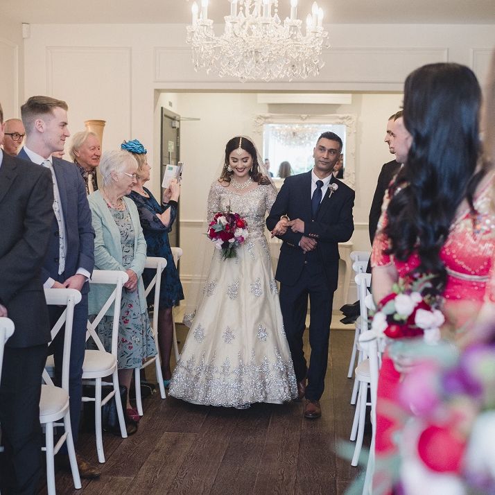 Bride walks down the altar at multicultural wedding with red bridesmaid dresses