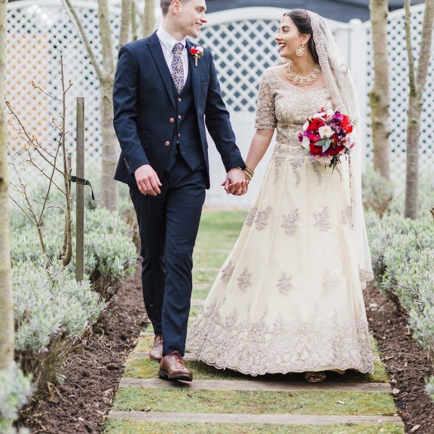 Bride and groom at fusion wedding with red bridesmaid dresses