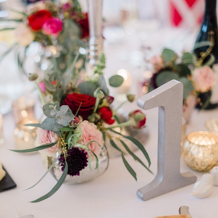 Bright wedding flowers at fusion wedding with red bridesmaid dresses