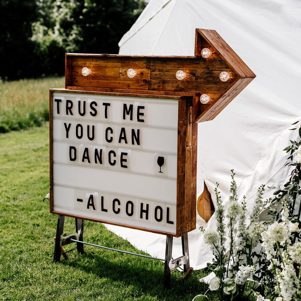Wooden Wedding Sign // Bride In Floral Dress By Stephanie Allin Festival Wedding With Food Trucks &amp; Outdoor Ceremony With Geo Dome Tent Baya Hire Epic Love Story Photography