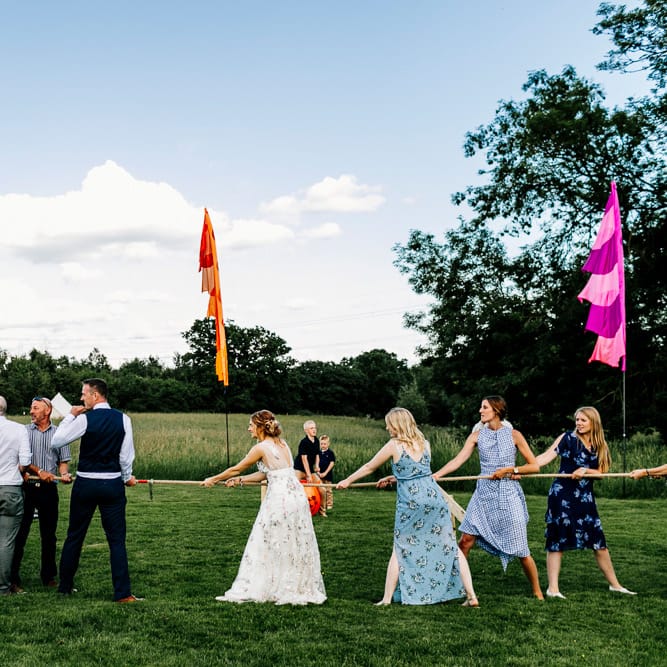 Tug Of War Wedding Games // Bride In Floral Dress By Stephanie Allin Festival Wedding With Food Trucks &amp; Outdoor Ceremony With Geo Dome Tent Baya Hire Epic Love Story Photography