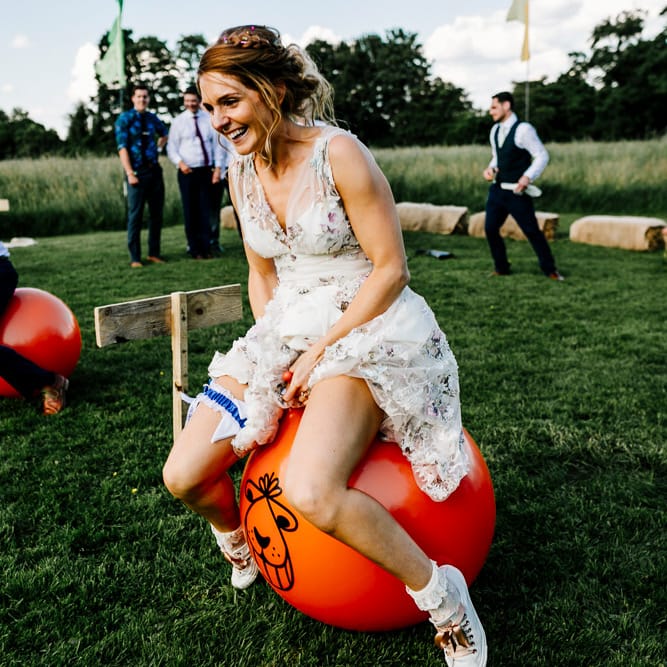 Space Hopper Race Wedding Games // Bride In Floral Dress By Stephanie Allin Festival Wedding With Food Trucks &amp; Outdoor Ceremony With Geo Dome Tent Baya Hire Epic Love Story Photography