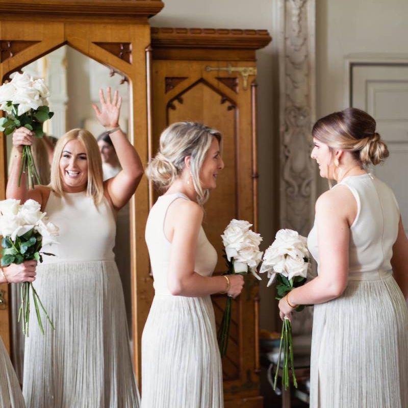 Bridesmaids wearing fringe dresses and white rose bouquets