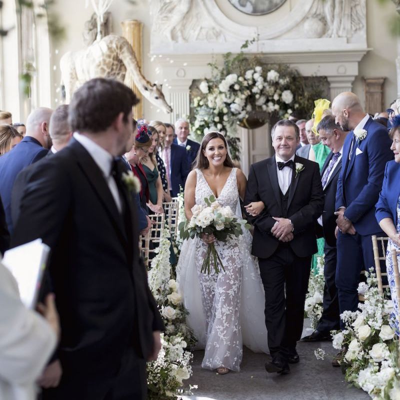 Bride walking down the aisle with white rose bouquet