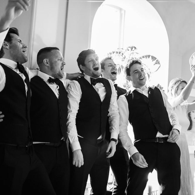 Groom celebrates with his groomsmen wearing bowties and waistcoats