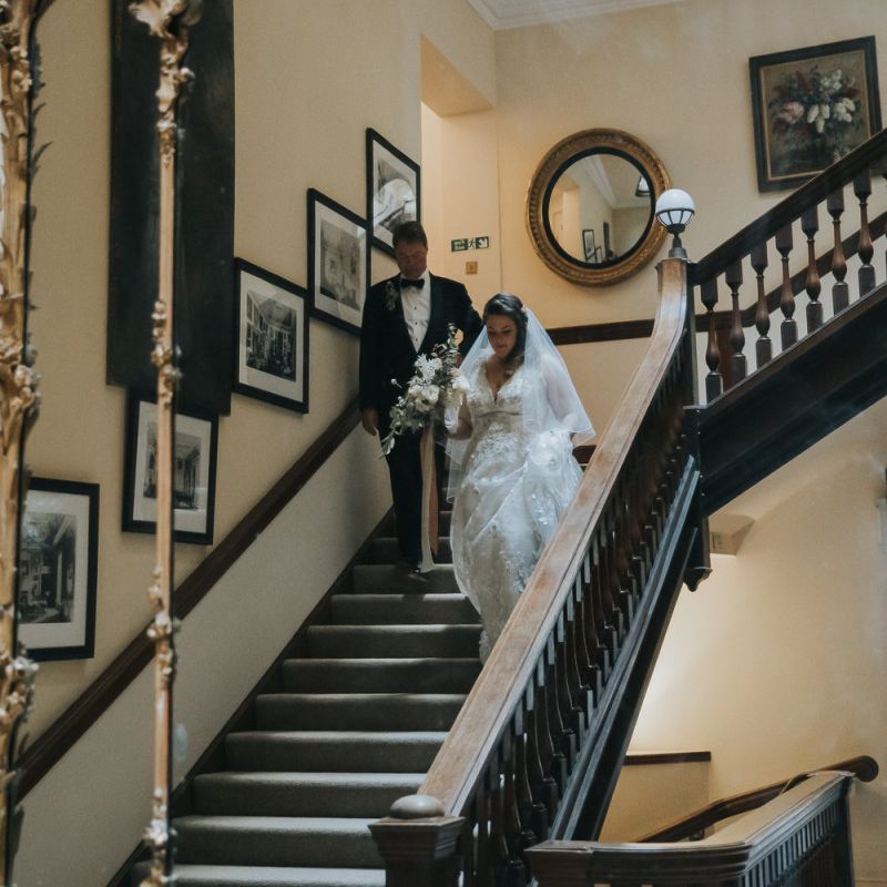 Bride Comes Down The Staircase With Father at Oxfordshire Wedding Venue