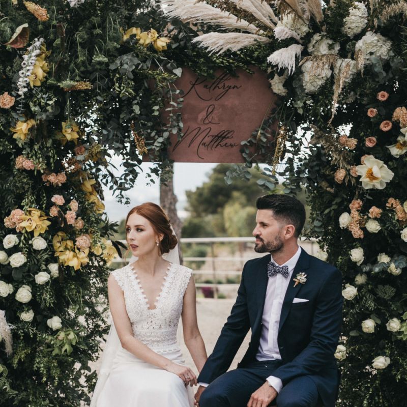 Bride in Pronovias Wedding Dress and Groom in Navy Suit Holding Hands During the Wedding Ceremony